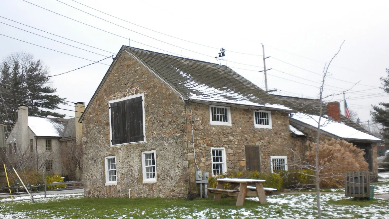 Historic stone farmhouse with a slate roof and snow on the ground