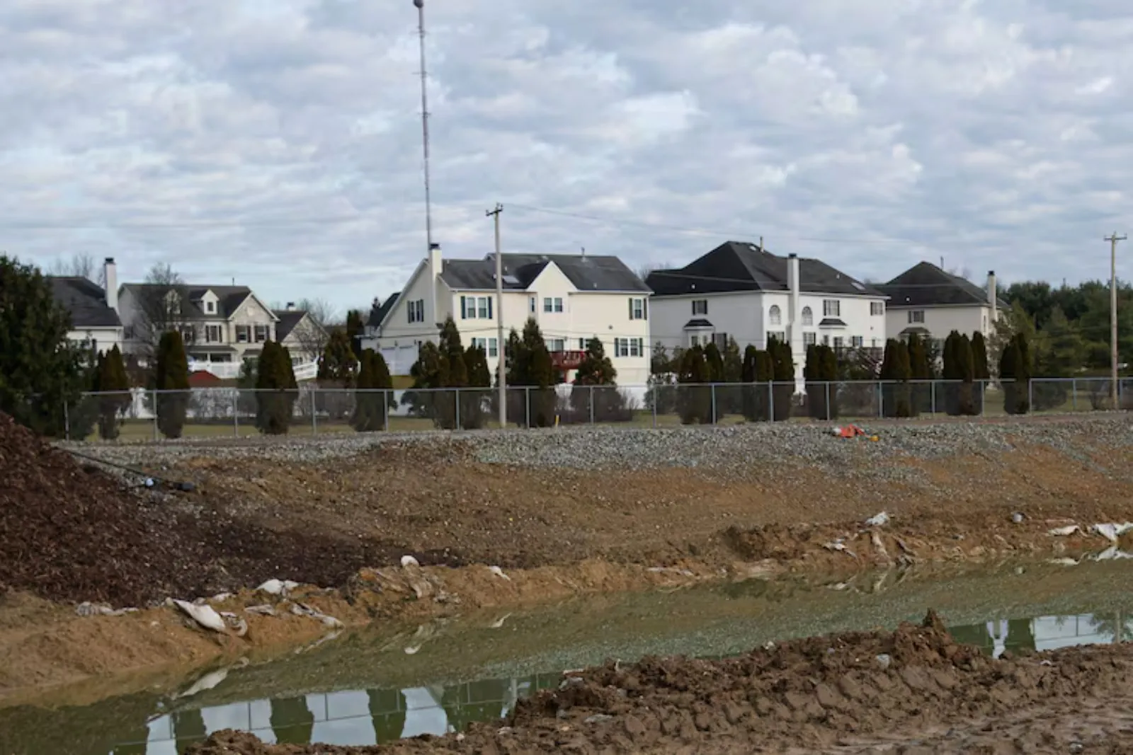 New white houses behind a fence and a cleared construction site