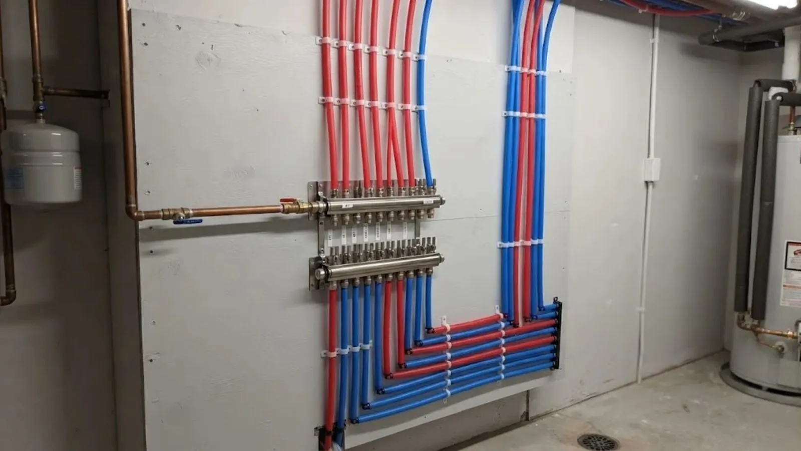 Red and blue PEX tubing running from a manifold on a utility wall