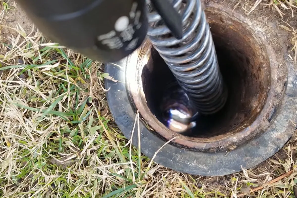 Drain cable feeding into a sewer cleanout in a lawn